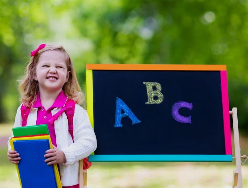 child smiling in front of blackboard